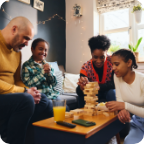 A family of four enjoy a game of Jenga together in their living room. 